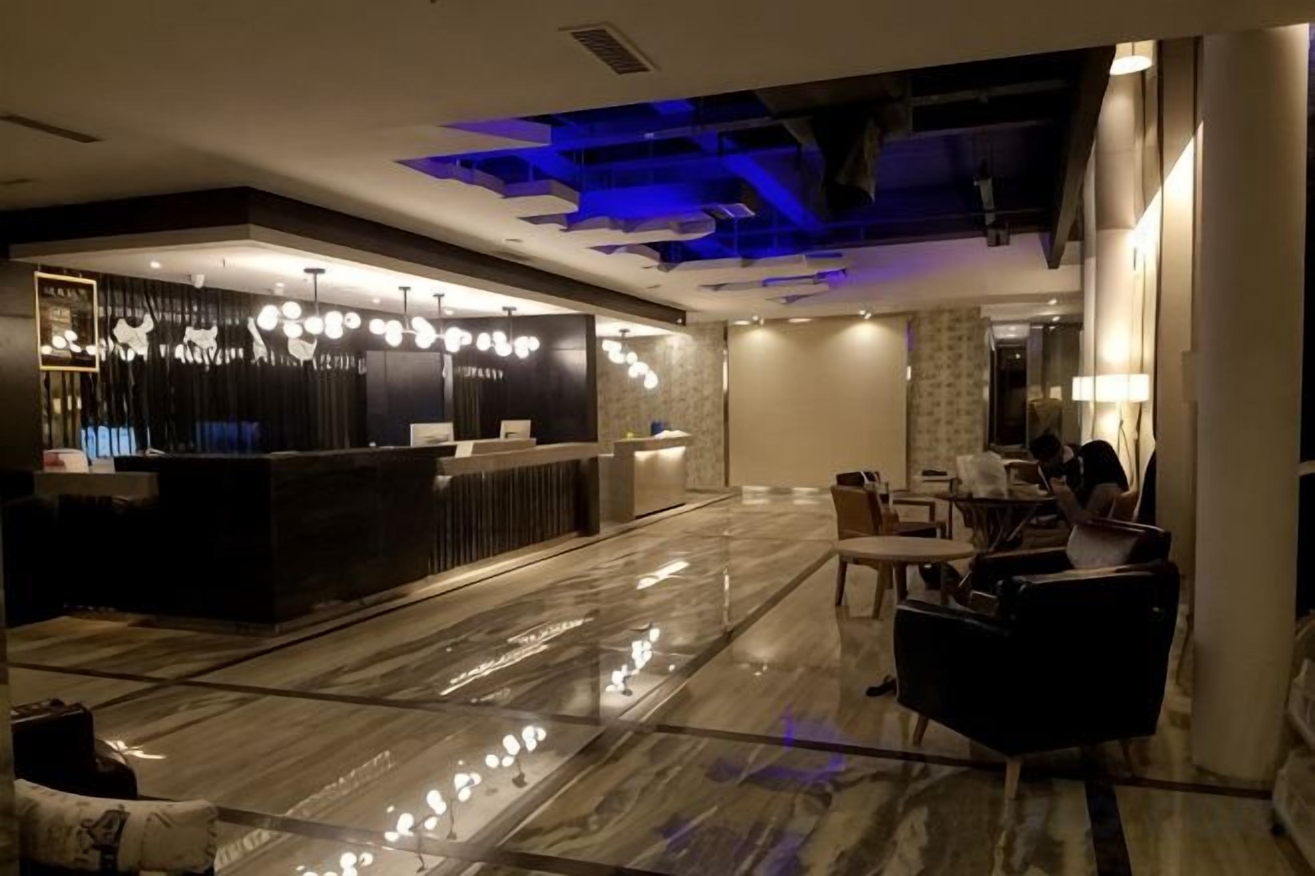 A hotel lobby with a reception desk, seating area, and a marble floor.