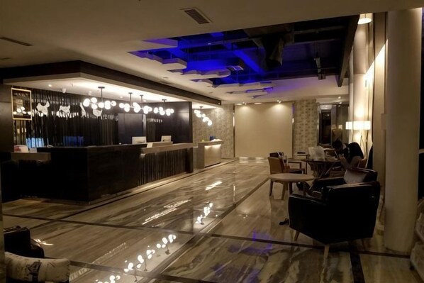 Un vestíbulo de hotel con mostrador de recepción, zona de estar y piso de mármol.