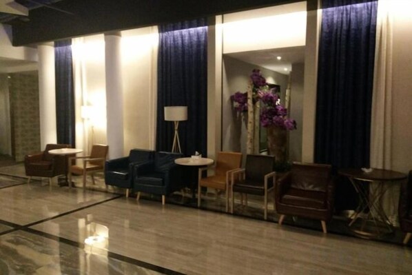 A hotel lobby with a seating area, a lamp, and a vase with flowers. - Zunyi Hengsheng Hotel (Yuqing)