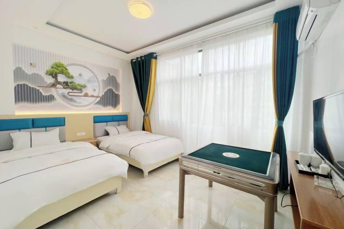A hotel room with two beds, a desk with a computer, a TV, and a wall mural.