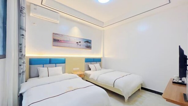 Habitación de hotel con dos camas, un escritorio, un televisor y un cuadro en la pared.