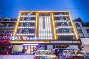 Un hotel de varios pisos con señalización iluminada y una fila de coches estacionados al frente.