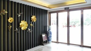 Een moderne lobby met verticale zwarte panelen, een grote vaas en een receptiebalie.