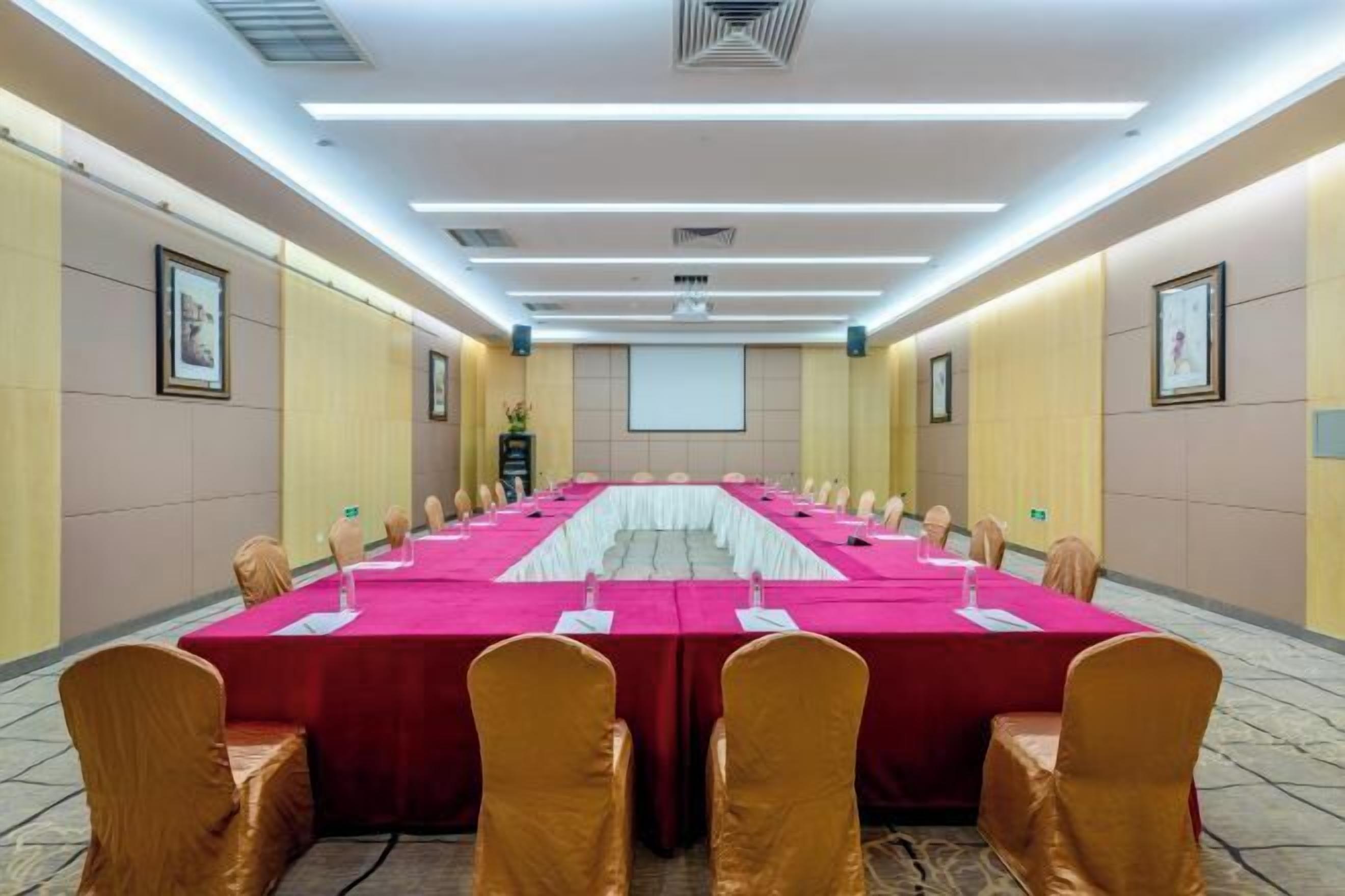 Une salle de conférence équipée d’une longue table, de chaises et d’un écran de projection.