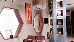 A modern hotel lobby with a large window, a geometric mirror, a chandelier, and a seating area with a table and chairs. - Anhui Construction New Era Hotel (Feidong)