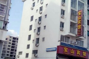A multi-story building with a prominent red sign indicating a hotel. - pingnanxianbaoshanbibgguan (Pingnan)