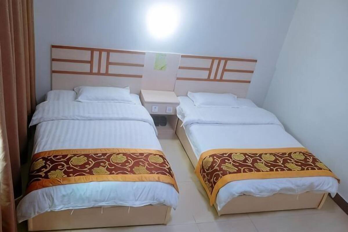 Dos camas individuales con cabeceros de madera, una mesita de noche y un aplique en la pared.