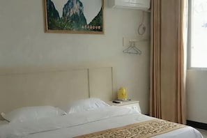 A hotel room with a bed, a bedside table with a phone, a wall-mounted air conditioner, and a window with curtains. - pingnanxianbaoshanbibgguan (Pingnan)