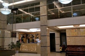 Un hall de hotel con mostrador de recepción, zona de estar y una escalera.