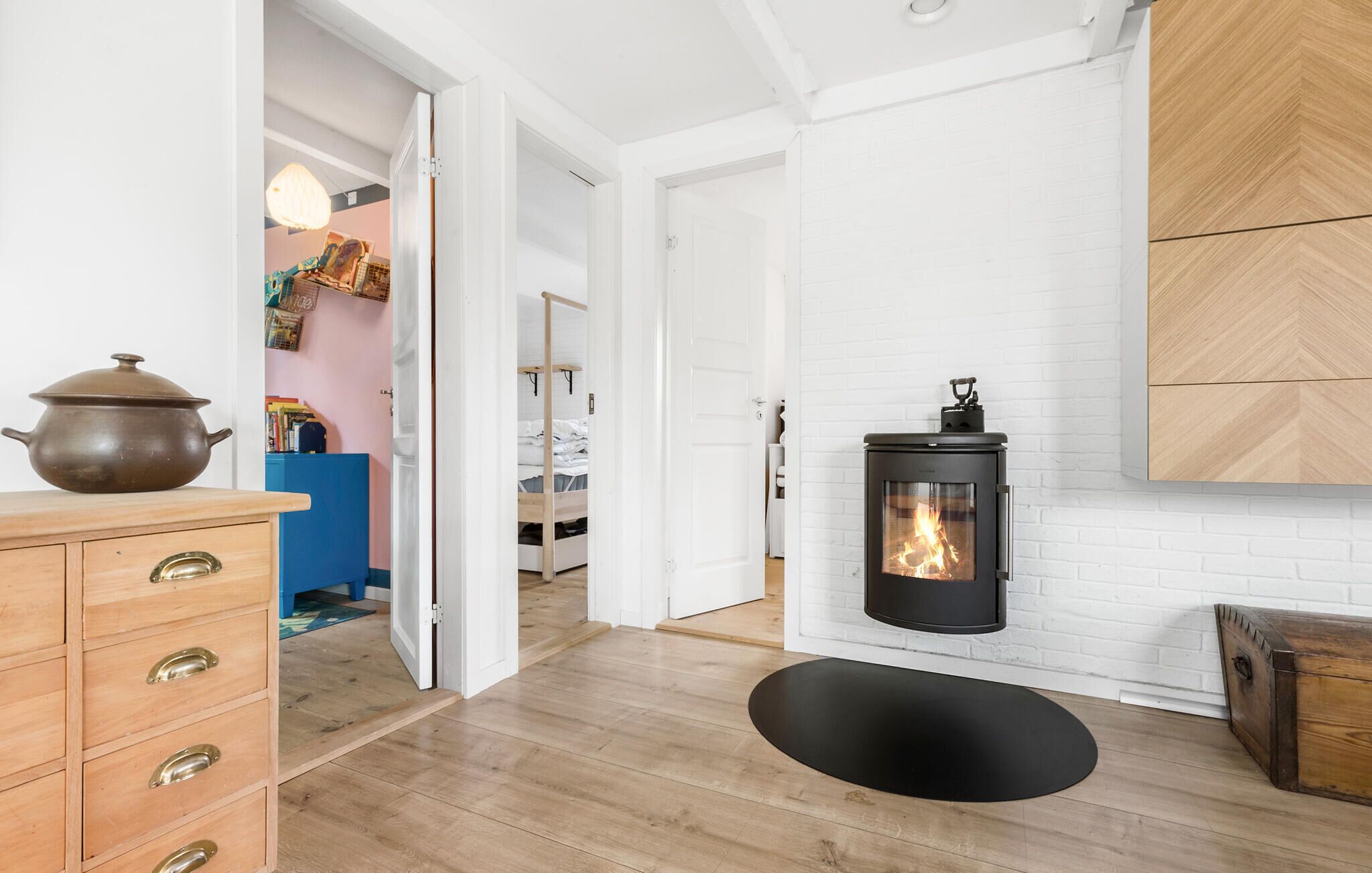 Ein modernes Interieur mit Kaminofen, Holzkommode und blauem Schrank.