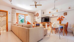 A modern living room with a sofa, TV, dining area, and decorative items. - Beach front home in Platja d'Aro with WiFi (Platja d'Aro)