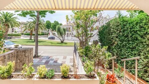 A balcony with a view of a residential street, a stone wall, and a variety of potted plants. - Beach front home in Platja d'Aro with WiFi (Platja d'Aro)
