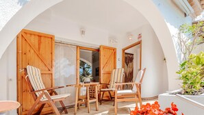 An outdoor patio with wooden furniture, including chairs and a table, under a white archway. - Beach front home in Platja d'Aro with WiFi (Platja d'Aro)
