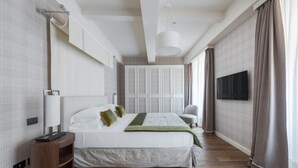 A modern hotel room with a large bed, a TV, a bedside table, and a window with curtains.