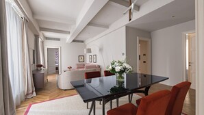 A modern dining area with a glass table, red chairs, and a vase of flowers.