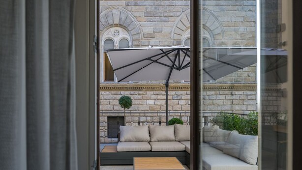 A modern outdoor seating area with a sofa, a wooden table, and a large umbrella.