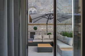 Un área de estar al aire libre moderna con un sofá, una mesa de madera y un paraguas grande.