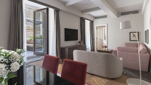 A modern living room with a sofa, a TV, and a dining area with chairs.