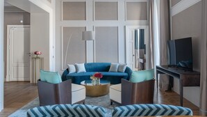 A modern living room with a blue sofa, two armchairs, a coffee table, and a TV on a stand.