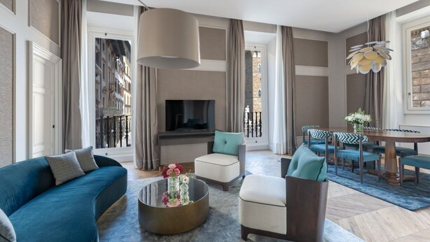 A modern living room with a sofa, armchairs, a coffee table, and a dining area with a table and chairs.