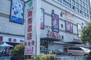 Un hotel con un letrero llamativo, varios banderines y un estacionamiento con vehículos.