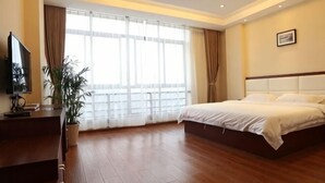 Een hotelkamer met een bed, een televisie, een bureau en een groot raam.