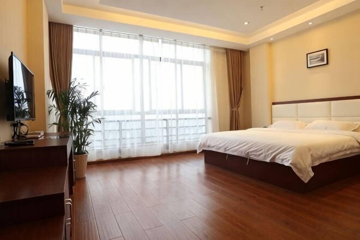 Een hotelkamer met een bed, een televisie, een bureau en een groot raam.