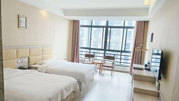 Een hotelkamer met twee bedden, een bureau, een stoel en een groot raam.