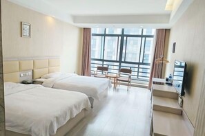 Een hotelkamer met twee bedden, een bureau, een stoel en een groot raam.