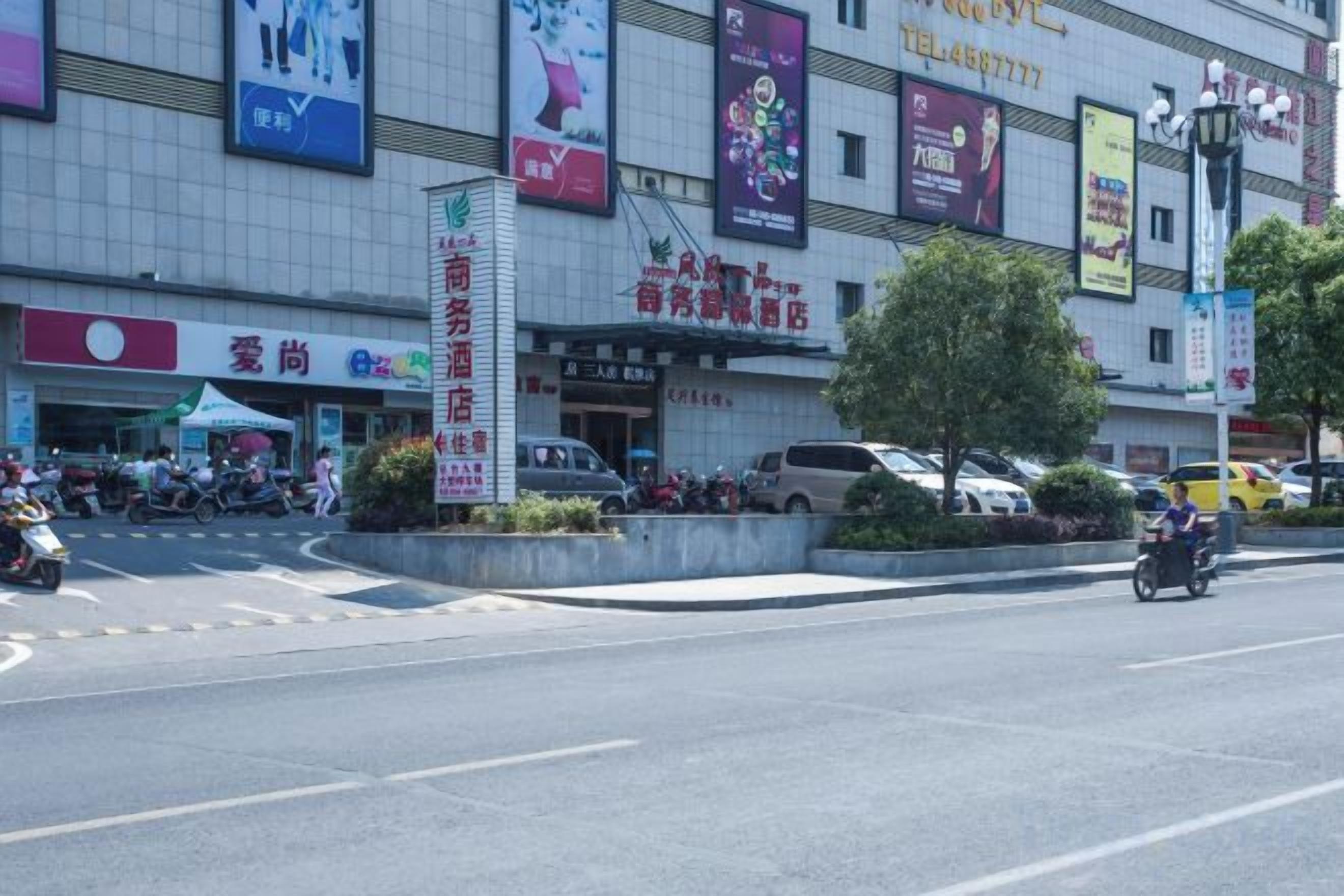 A street with a building featuring multiple signs and a large vertical sign.