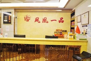 Ein Empfangsbereich mit Empfangstresen, Stühlen und einer Wand mit chinesischen Schriftzeichen.