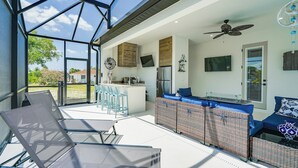 Un espace cuisine extérieur moderne, doté d’un bar, de sièges et d’un ventilateur de plafond.