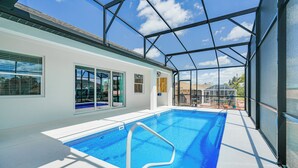 Une piscine intérieure à l’eau d’un bleu cristallin, entourée d’une paroi de verre, offrant une vue sur le paysage extérieur.