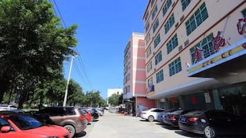 A multi-story building with a row of parked cars on the street.