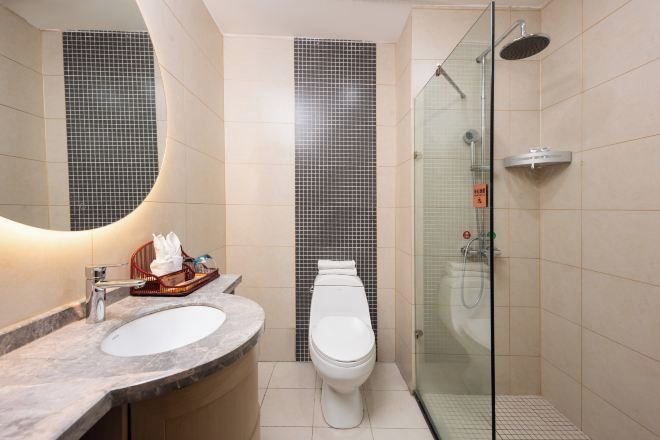Een moderne badkamer met een glazen douchecabine, een wit toilet en een marmeren wastafel.