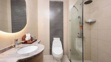 Een moderne badkamer met een glazen douchecabine, een wit toilet en een marmeren wastafel.