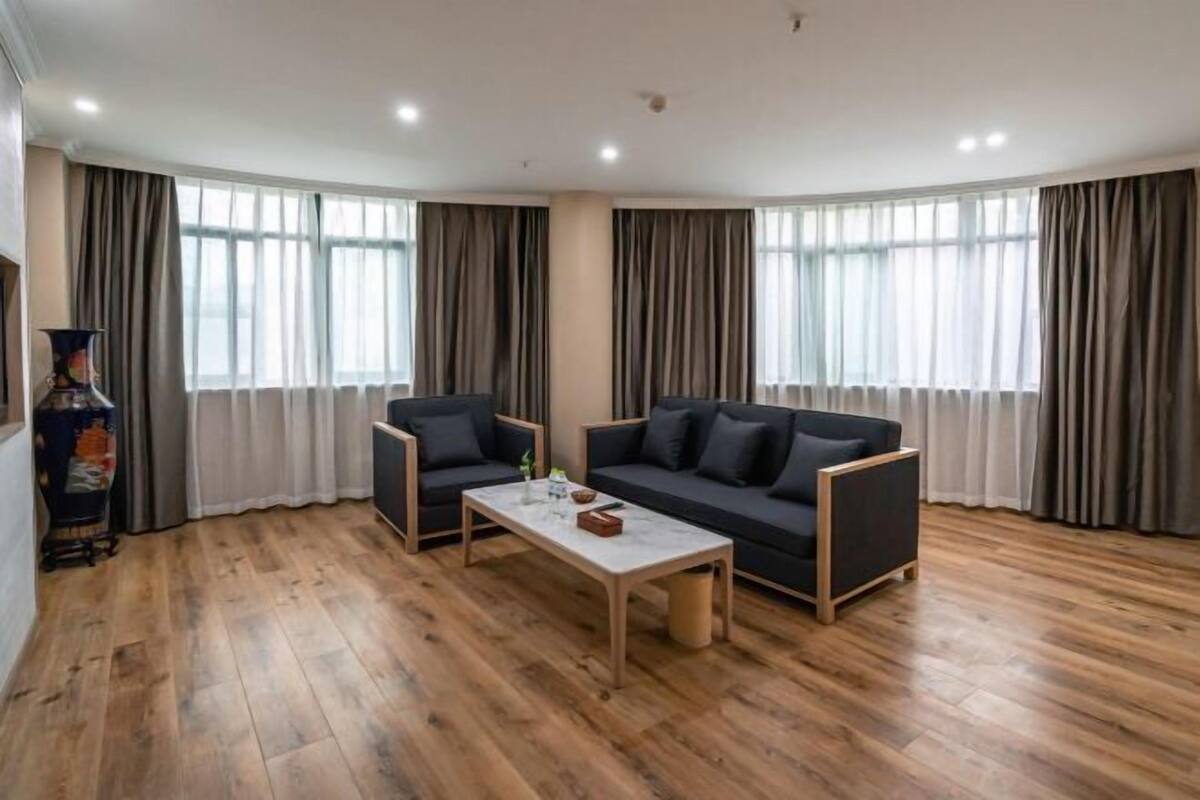 Ein modernes Wohnzimmer mit einer Couch, zwei Sesseln, einem Couchtisch und Holzboden.