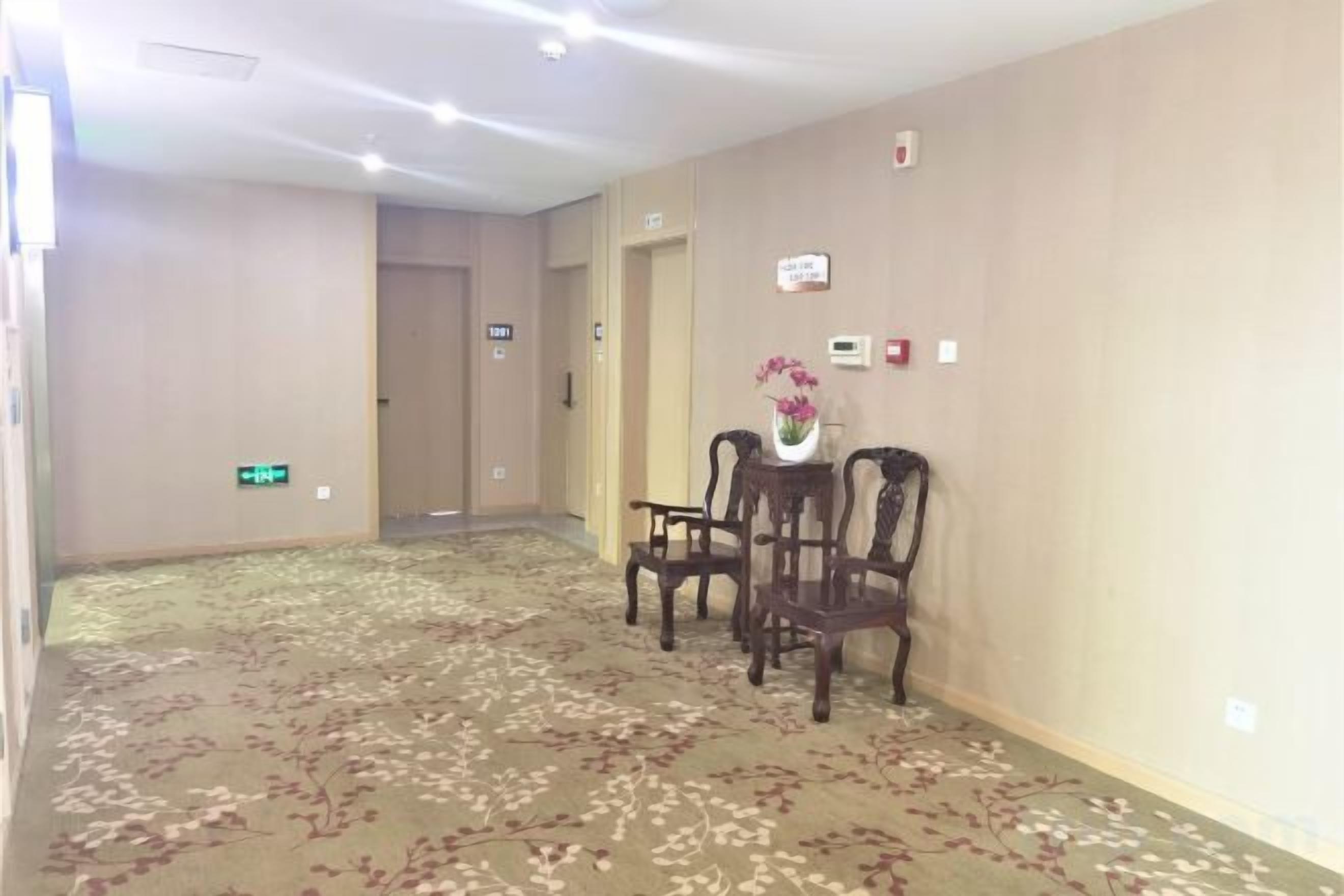 A hotel hallway with a carpeted floor, a reception desk, and a door marked '1011'.