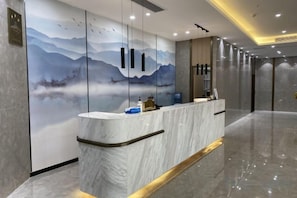 A reception desk with a marble counter, a wall mural, and a modern interior design.