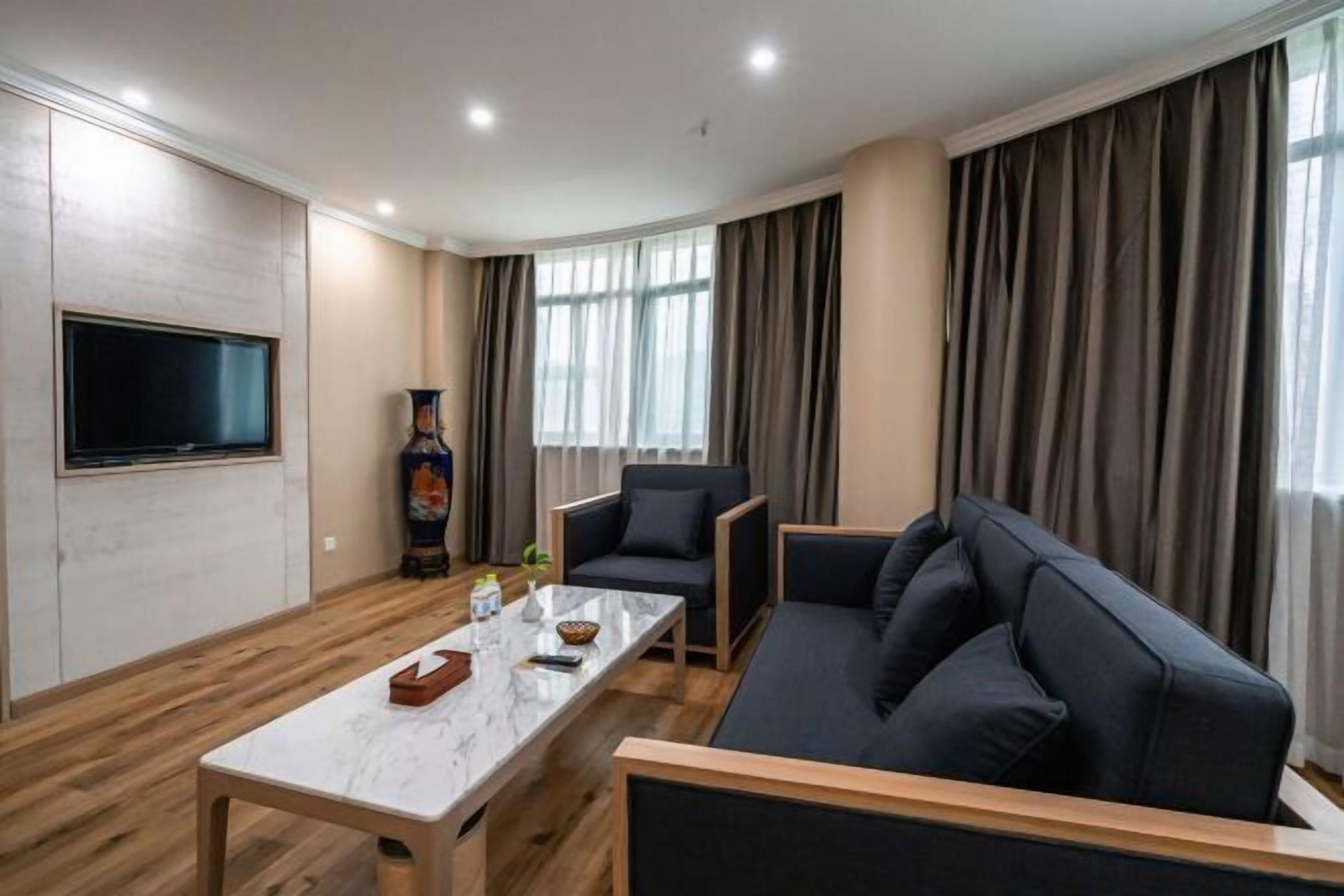 Ein modernes Wohnzimmer mit Flachbildfernseher, Marmortisch, einer Couch und einem Sessel.