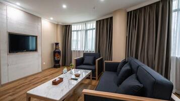 Ein modernes Wohnzimmer mit Flachbildfernseher, Marmortisch, einer Couch und einem Sessel.
