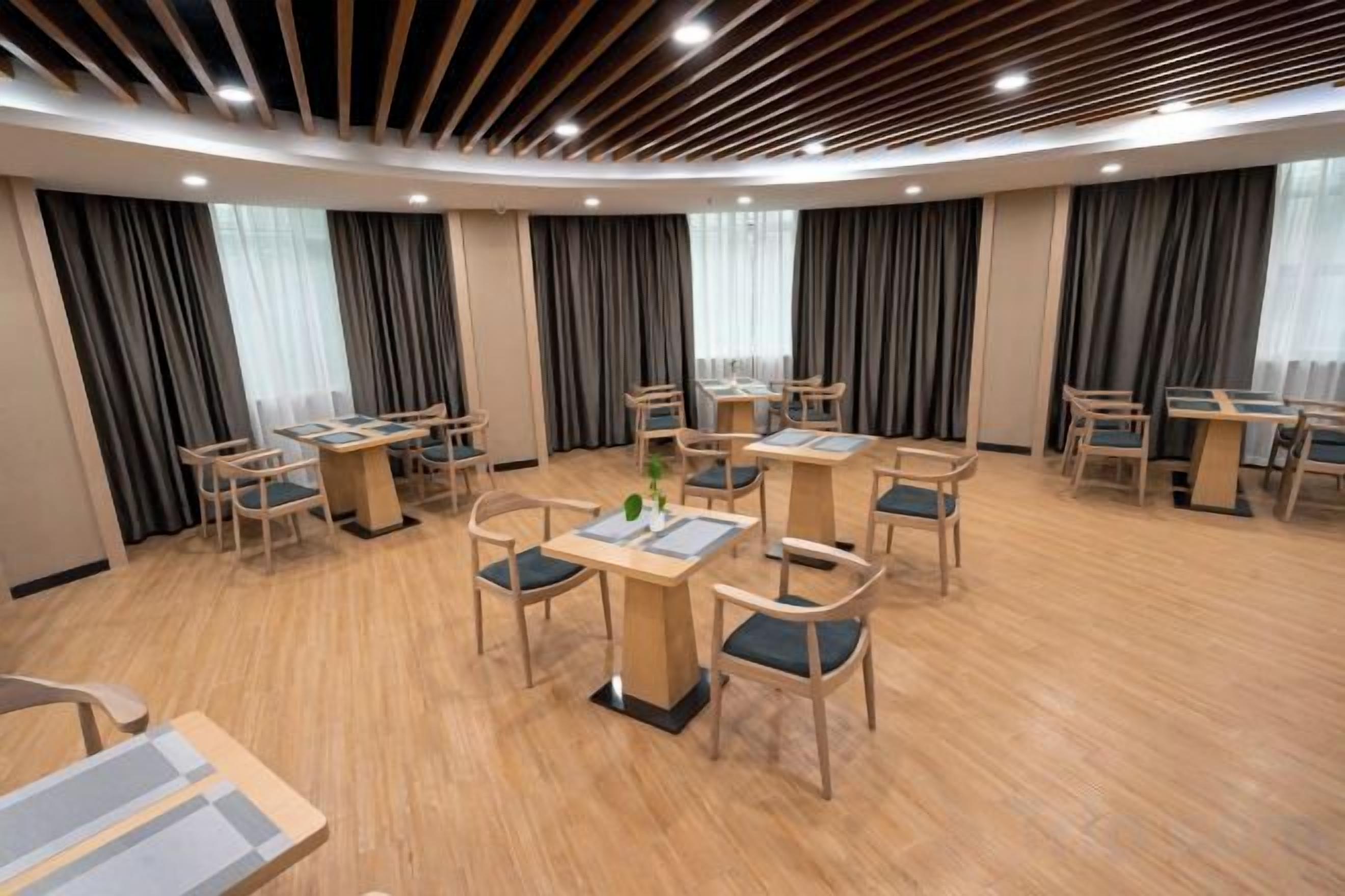 Una habitación de hotel con una mesa de comedor redonda, sillas y suelo de madera.