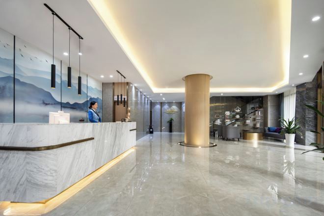 Un hall d’hôtel moderne avec un comptoir de réception en marbre, une grande colonne et un espace salon comprenant des canapés et une table basse.