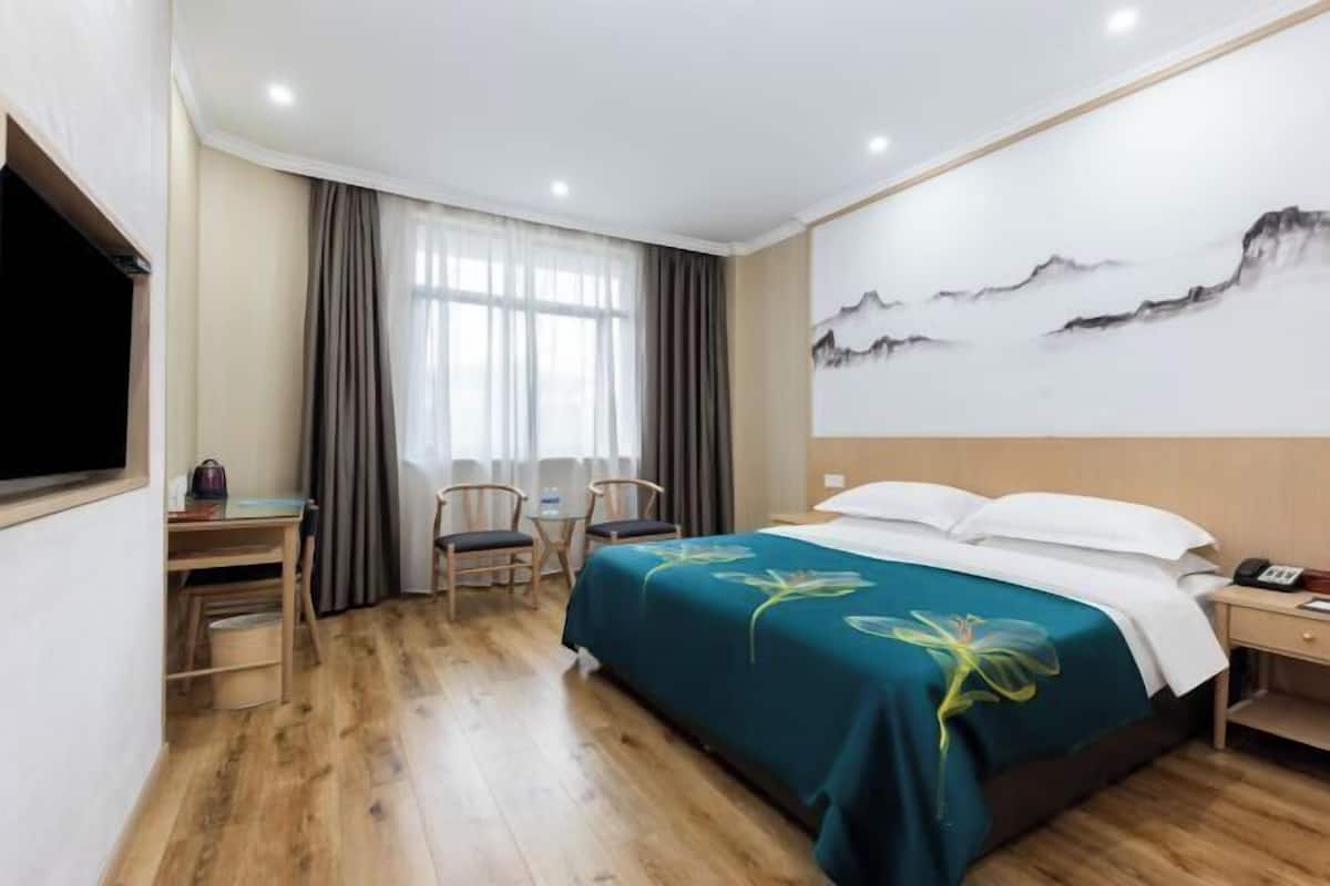 Ein Hotelzimmer mit Bett, Schreibtisch, Stühlen und einem Bild an der Wand.