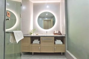 A modern bathroom with a vanity, a round mirror, and a glass shower enclosure. - Xinhua Hotel Nanchuan (Chongqing)