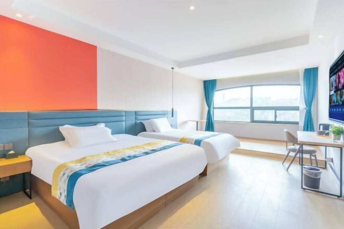 Een hotelkamer met twee bedden, een bureau en een groot raam.