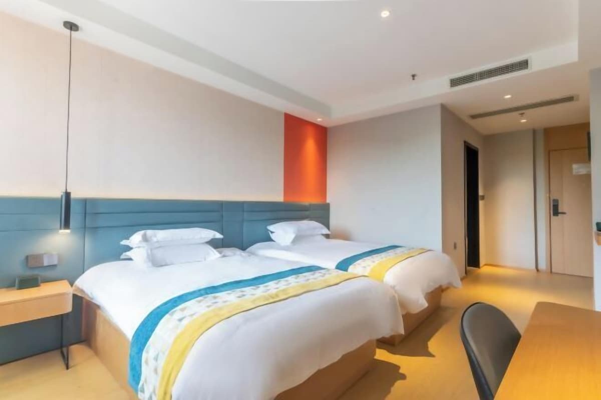 Habitación de hotel con dos camas, un escritorio y una silla.