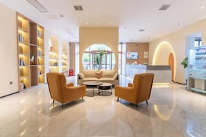 A hotel lobby with a reception desk, seating area, and bookshelves. - Shanghai Jiuting Yo Yi Hotel (Shanghai)