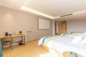 Una habitación de hotel con escritorio, dos camas, una silla y televisión en la pared.