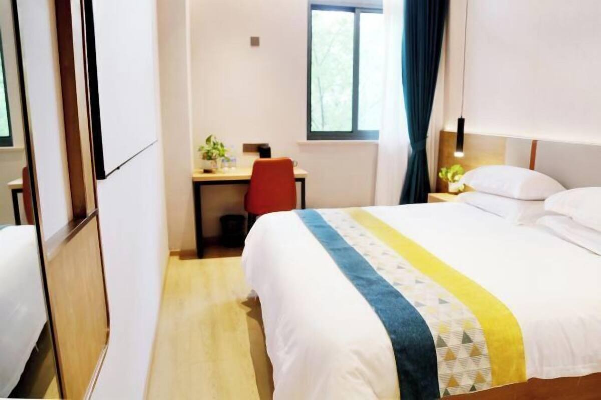 Een hotelkamer met een bed, een bureau en een raam.